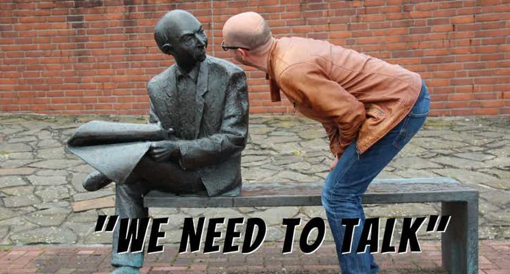 Man bent-over, face-to-face, talking to a statue of a man sitting on a bench. "We Need to Talk" text on bottom of image.