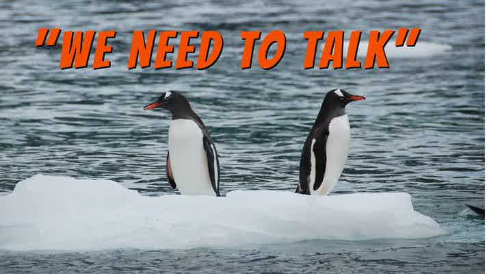 Two penguins on an ice floe, facing in opposite directions, with a caption that says, "We Need to Talk"