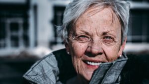 Head shot of fit, smiling older woman wearing grey jacket