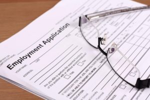 Blank employment application on table, with reading glasses