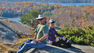 Older man and woman hikers sitting on a scenic rocky point
