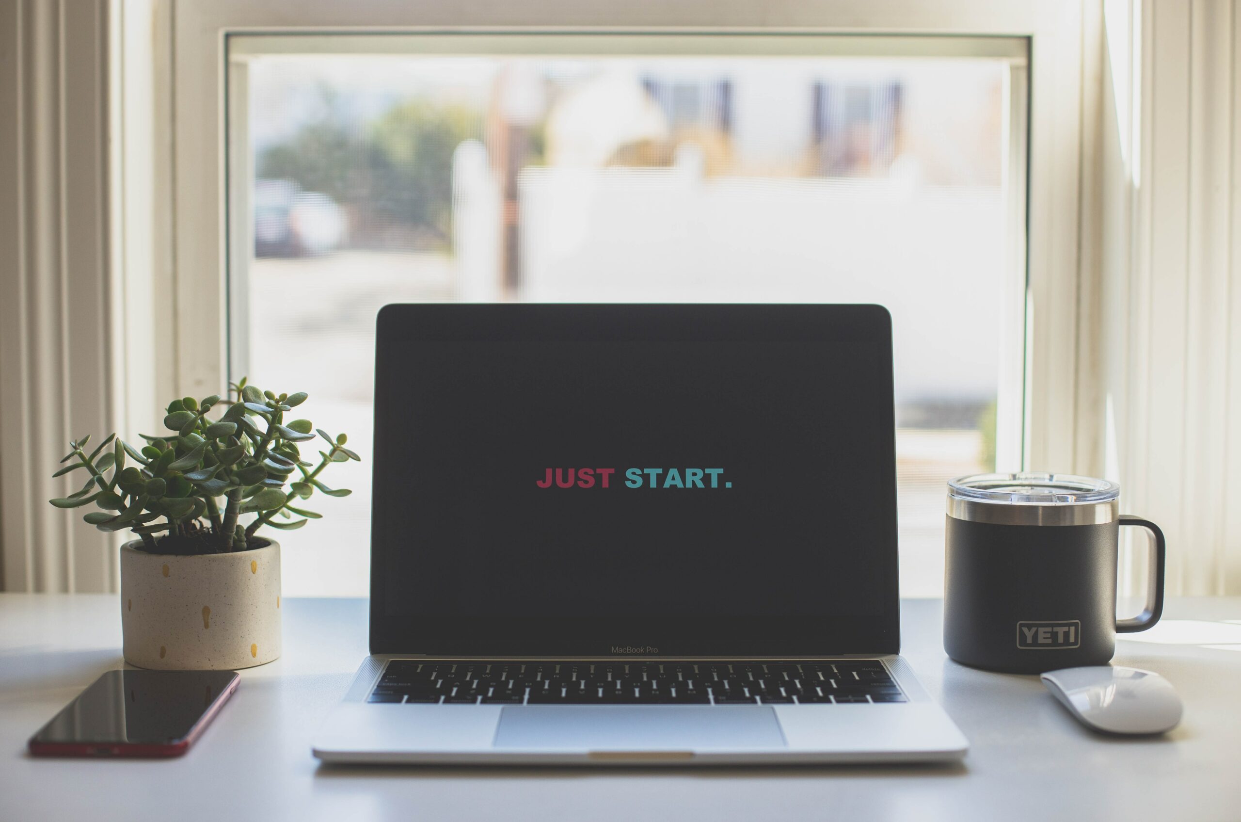 Desk top with open laptop that says, just start