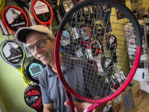 Man holding tennis raquet in store