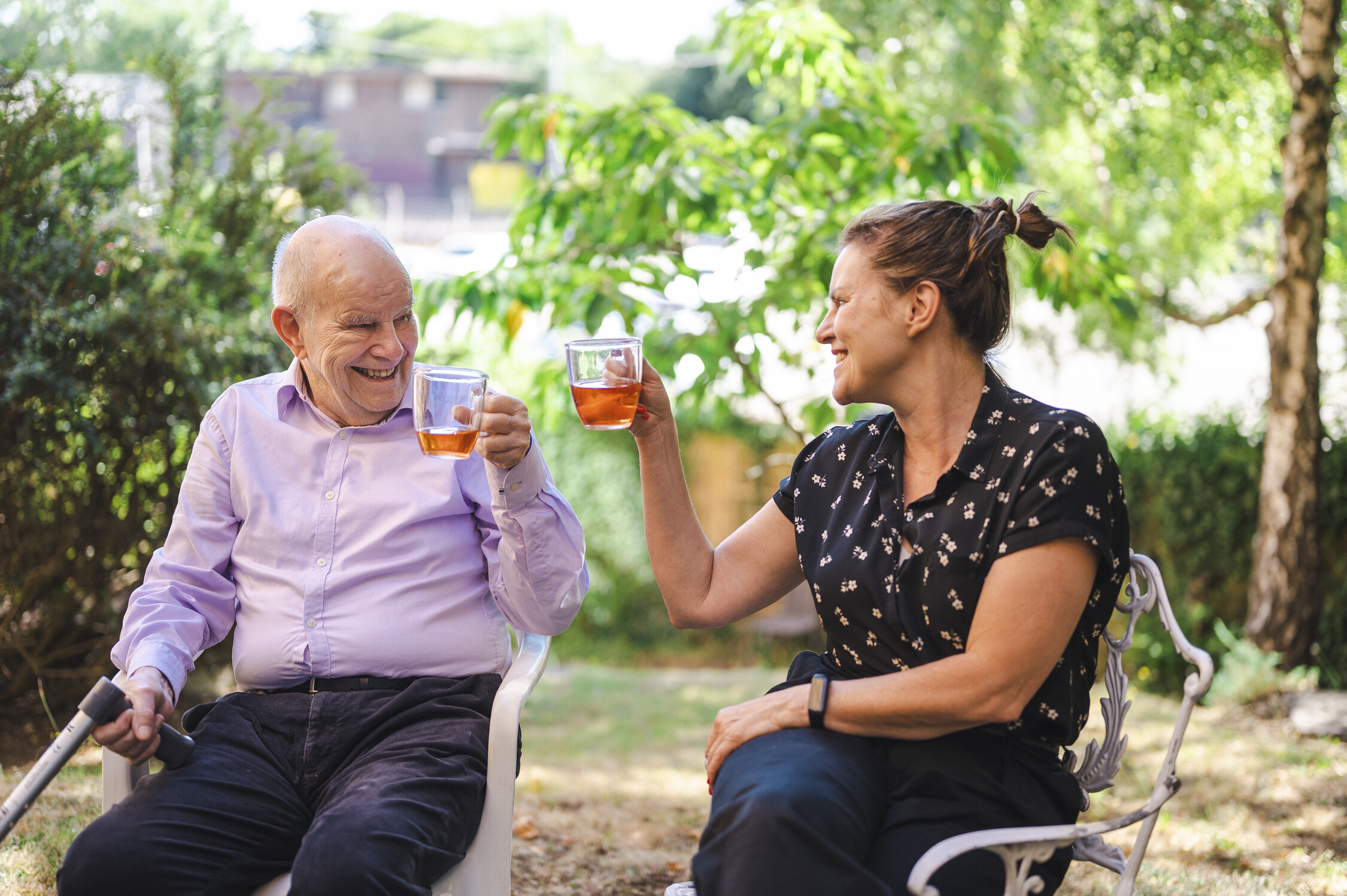 Older man and daughter smiling and raising glasses of iced tea in a toast